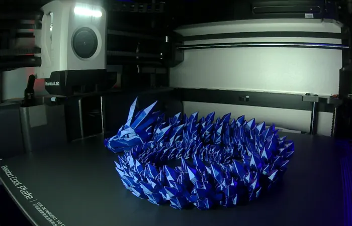 A blue dragon, just printed, on the print bed in our shop